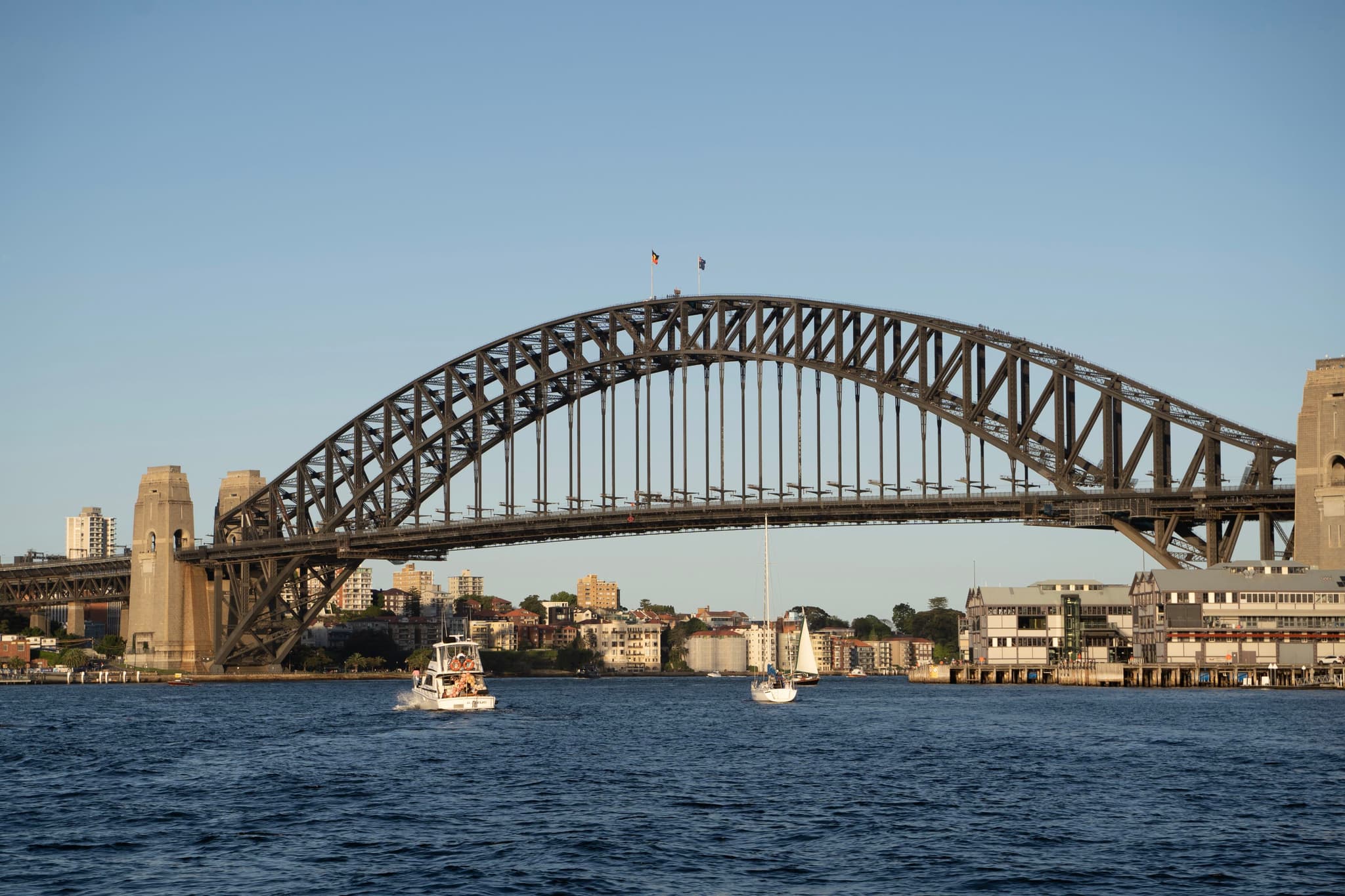 Sydney Harbour Bridge spanning across the water with boats in the foreground and city buildings in the background