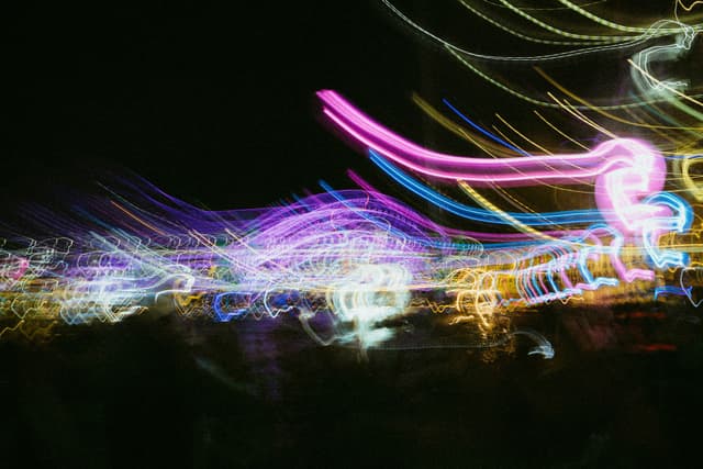 A colorful, abstract display of blurred lights against a dark background, creating a dynamic and vibrant effect