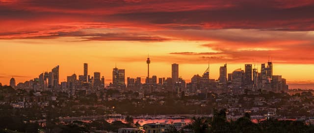A city skyline at sunset with a dramatic orange and red sky
